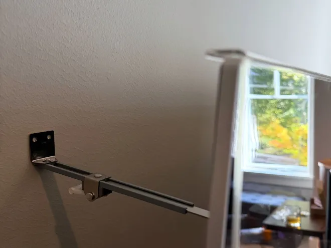 The top edge of the acrylic protector hooked over the upstairs TV, with the brace behind it.