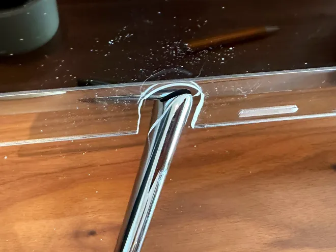 The notch cut in the acrylic sheet to clear the TV's leg. The edges are rough.